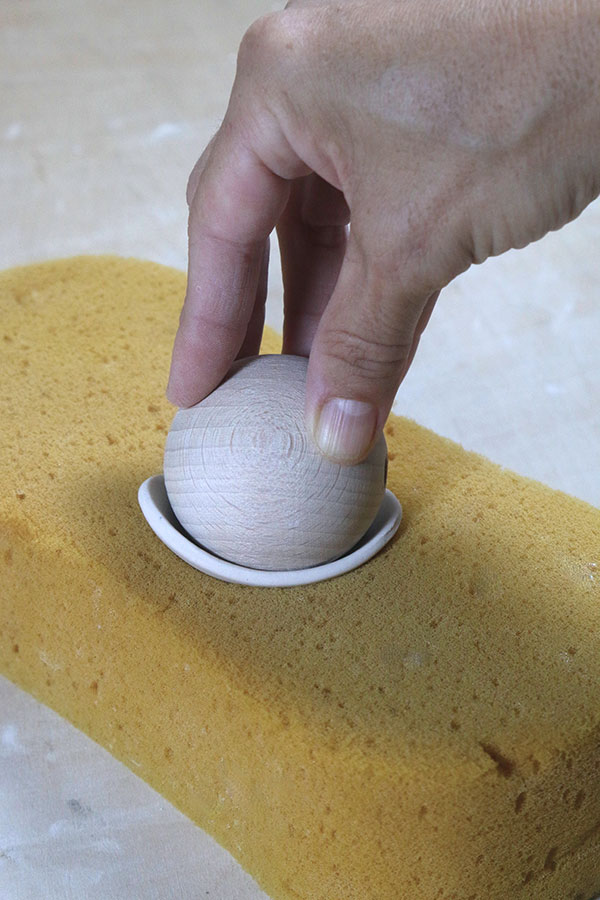 6 Place the oval slab over a piece of foam, then create a dome shape by pressing a wooden ball down on the slab.