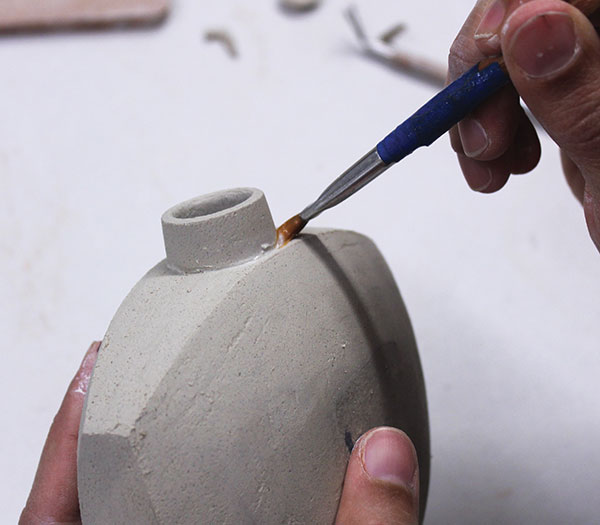 7 After cutting the hole in the flask body, score, slip, and attach the neck. Use a firm brush to compress the join.