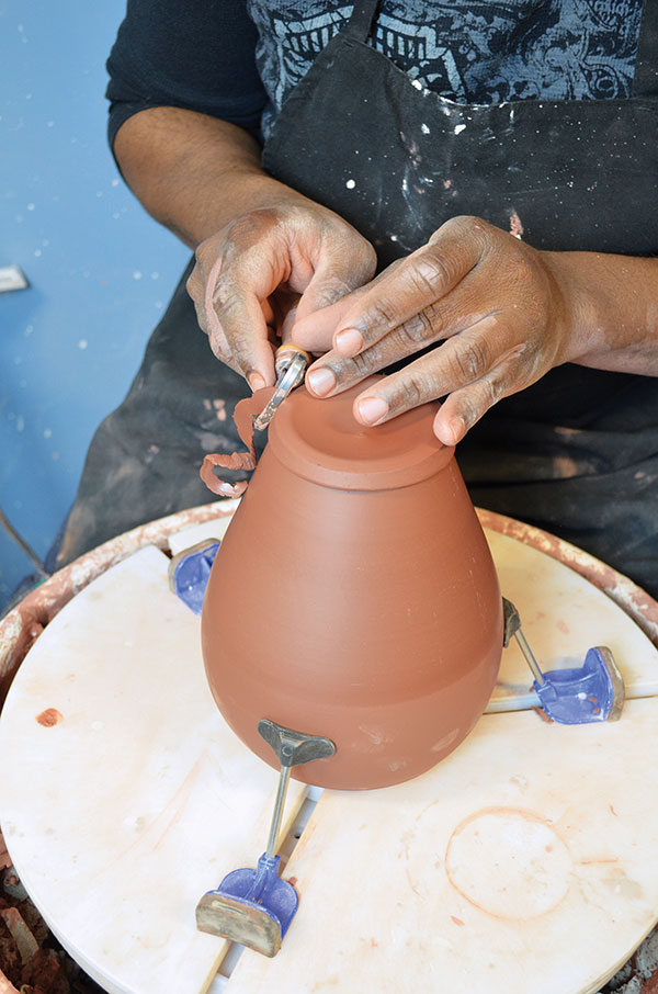 5 With the wheel moving, trim the excess clay from the bottom edge of the pot.