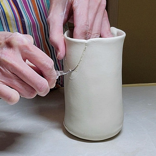 8 Cut the pitcher wall just inside the spout’s slip mark, then smooth the edges.