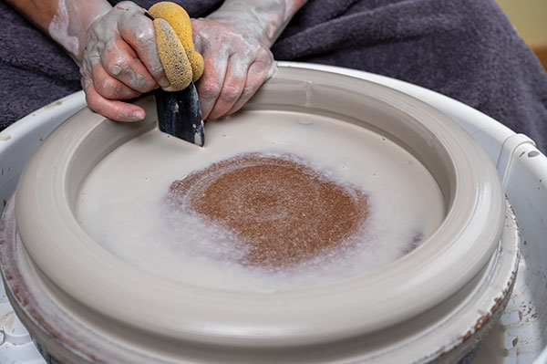 1 Open the clay to the wheelhead, then, keeping the rib flat on the bat and the left hand lubricated, pull the clay toward you to form a ring.