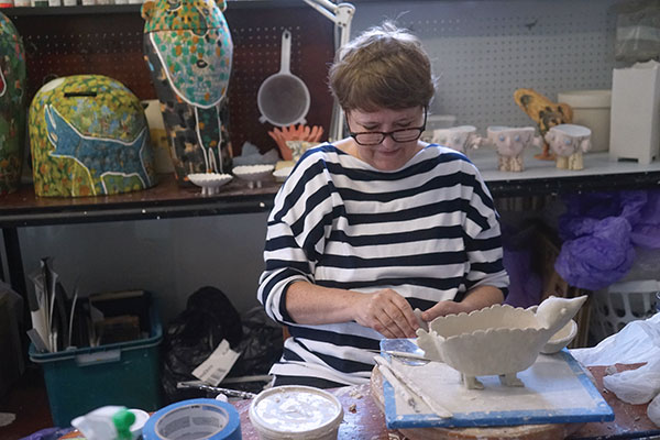 3 Pru Morrison in the studio handbuilding a stoneware bird bowl, 2021. Photo: Peter Fischmann.