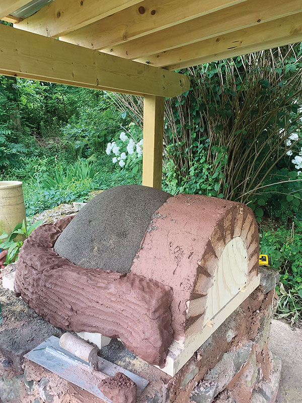 11.Coil pack a tight layer of clay and sand onto the dome, making a 4-inch wall.