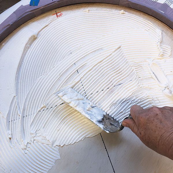 13 Spread a thin coat of tile adhesive on the primed background board.