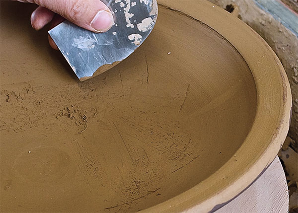 7 If you are using a coarse clay body with grog, use a metal rib to scrape the smooth, thrown surface to create texture.