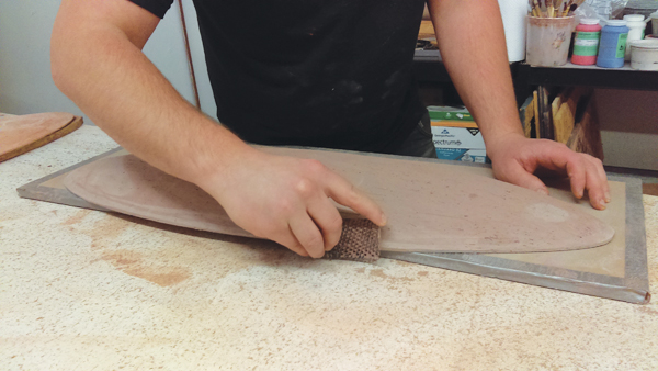 4 Once the slab sets up, pull it off the plywood and cut off the excess clay. Surform the leather-hard mold into the desired shape.