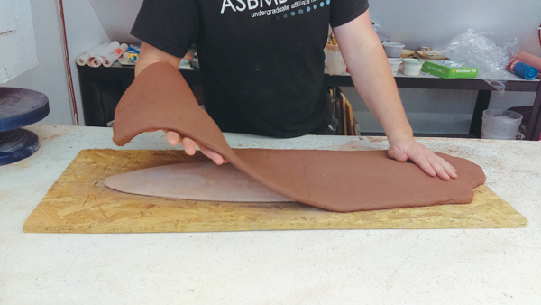 5 Place the bisque-fired mold on the plywood oval and the slump mold and cover it with a freshly rolled slab.