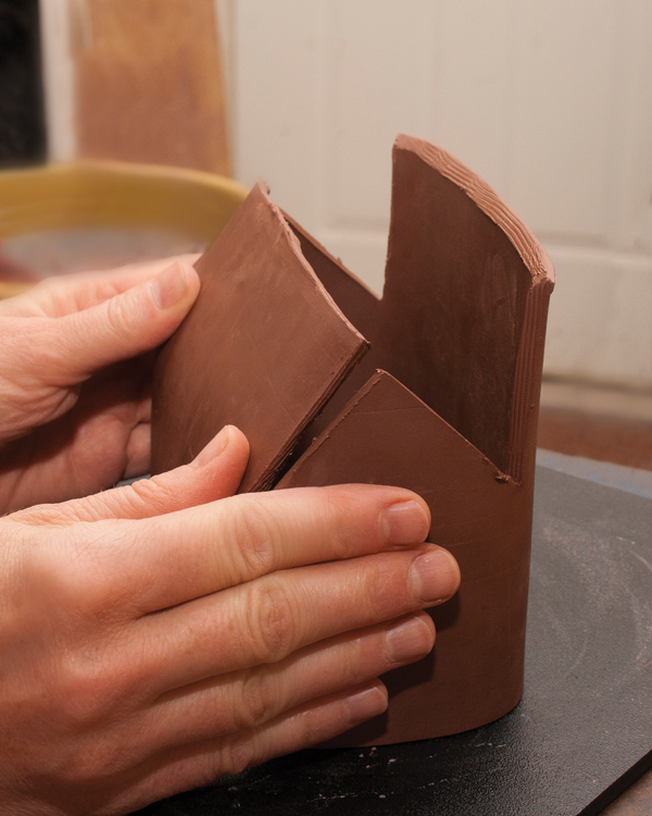 4 Hold the sides of the house with your palms and use your thumbs to fold the roof clay down beginning at the eaves.