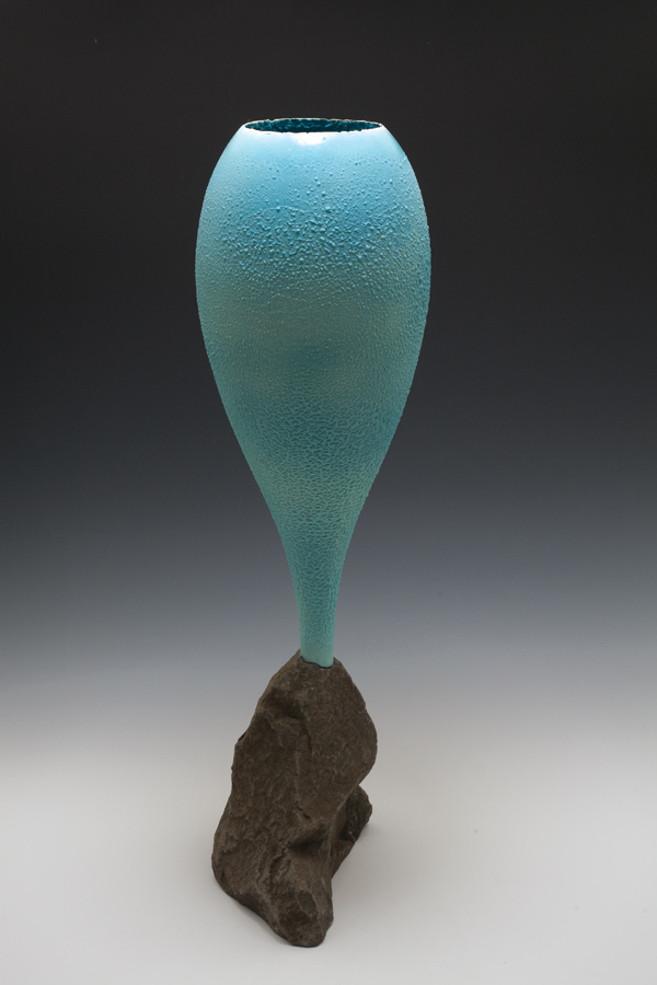 One-piece chalice with blue underglaze and white crawl glaze applied over top, mounted in a found and altered rock.
