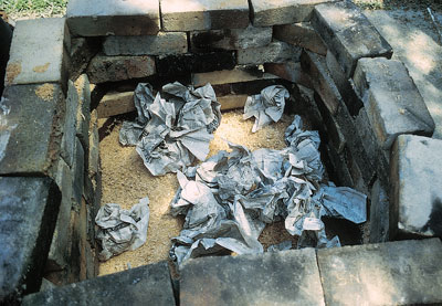 Placing wadded up newspapers on the sawdust to start the fire.