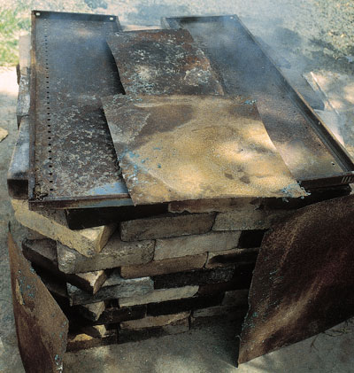 Covering the fire with sheets of metal after the sawdust has been ignited.