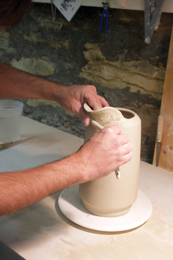 3 Add a slab of clay to the form to make a spout, then reinforce it with a coil.