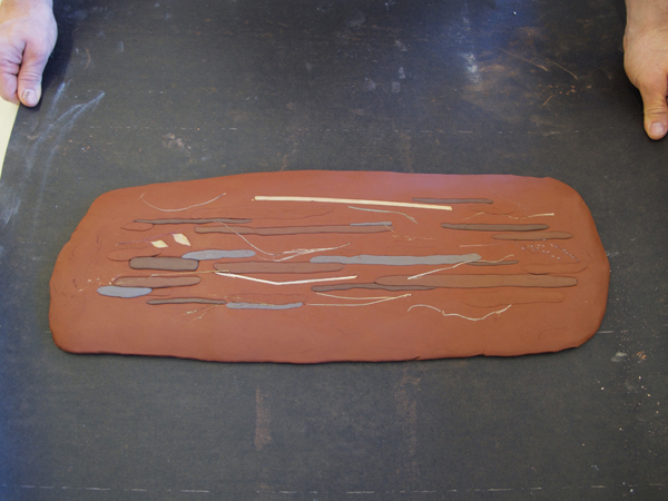 The slab, added coils of clay, and organic material have been compressed and the slab is now ready to stiffen up.