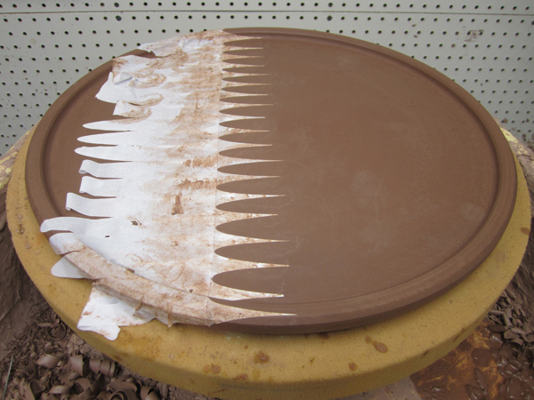 1 Alex throws and trims a wide terra-cotta tray. Meredith applies a paper stencil to the leather-hard surface.