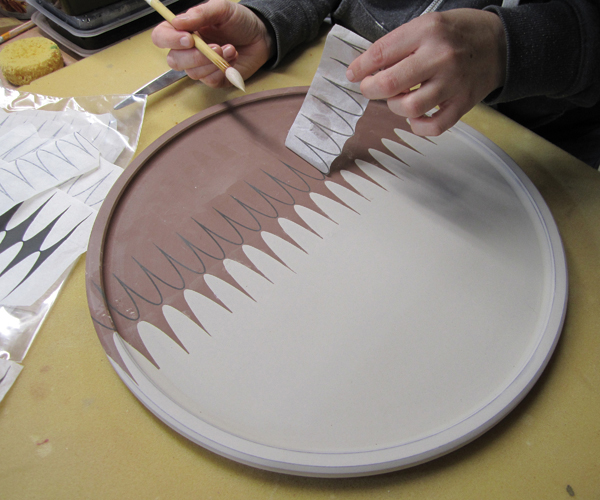 3 Meredith applies an underglaze tissue transfer and hydrates it to transfer the pattern. The tray is dried and bisque fired.