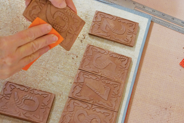 7 Run a piece of craft foam over the edges of the tile to burnish the clay and remove any sharpness before glazing.