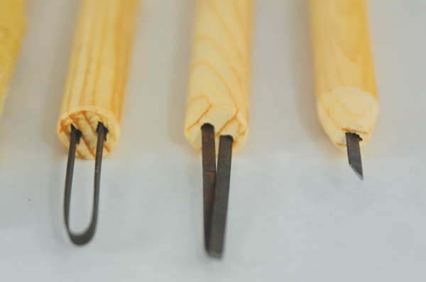 Detail of  carving/trimming tools: a bent L shape and a small rounded curve.