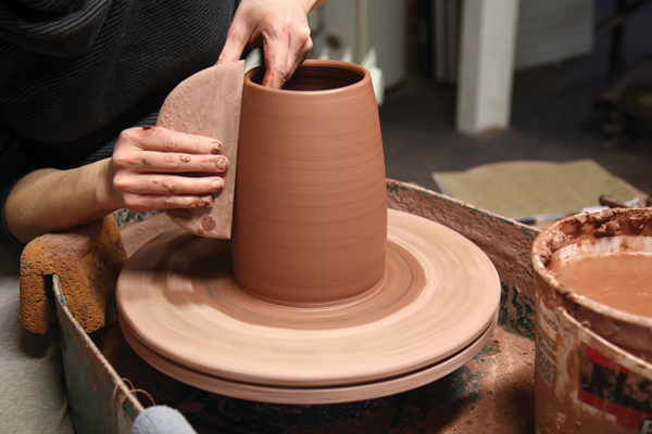 1 Use a large wooden rib to shape a tall cylinder for the body of the canister and to smooth the surface.