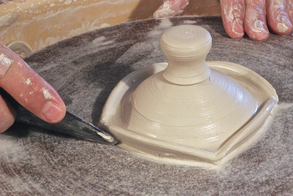 E Add a small piece of clay to the top and throw it into a knob, then define the edge.