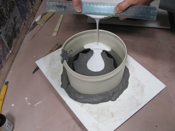 4 Pour plaster over the form. It helps to hold a plastic ruler at the edge of the bucket while pouring to get a cleaner cast.