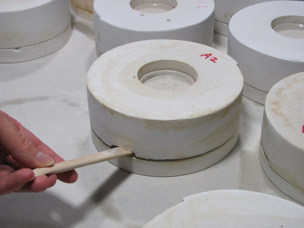 10 Wait until the cast bowl is ready to come out of the mold, then push a wooden stick into the lock release to open the mold.