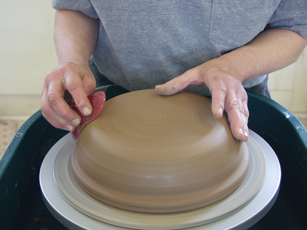 3 Turn the leather-hard pot over and trim it to round out the transition from floor to wall. Use a rib to smooth the trimmed area.