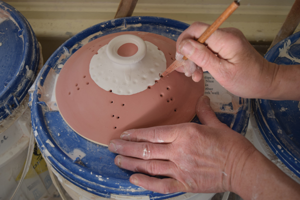 11 Wax the gallery, foot, and rim of the lid, then glaze the bowl. Remove any clogged glaze from all the holes.
