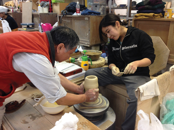2 Professor Shimada helping a third-year student throw porcelain for the first time at his annual demonstration.