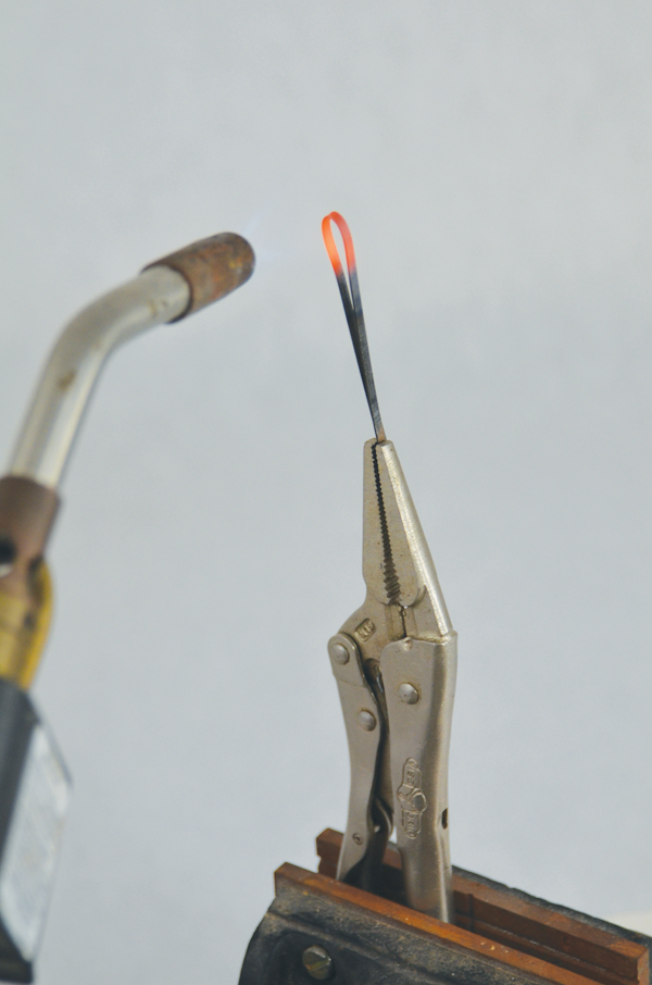 While holding the metal loop tool with flat-nose pliers, heat it with a propane torch, then bend it into a U shape.