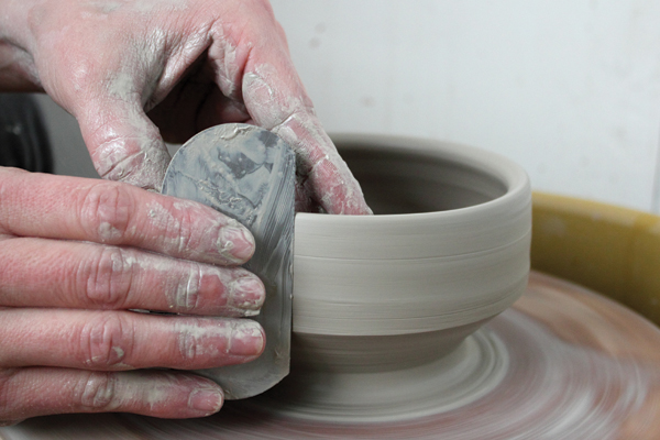 6 Center and open 1 1/2 pounds of clay for a lid. Open the mound, pull up the wall, and shape the lid with a rib. Check the width.