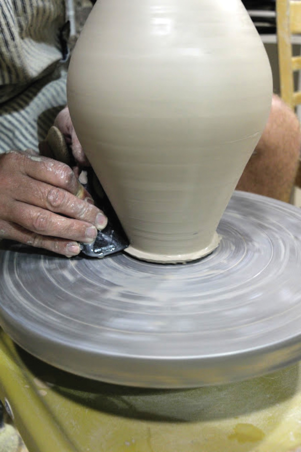 4 Trim away the excess clay, then refine the foot using the corner of a wooden rib.