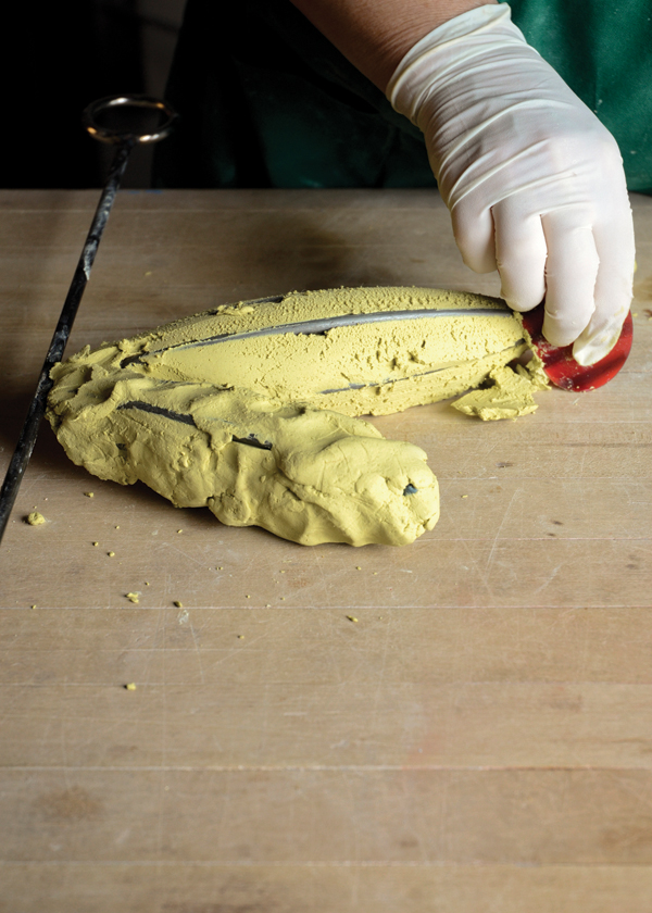 Sigel using a soft rib to compress the Egyptian paste and remove excess to reveal the steel supports.