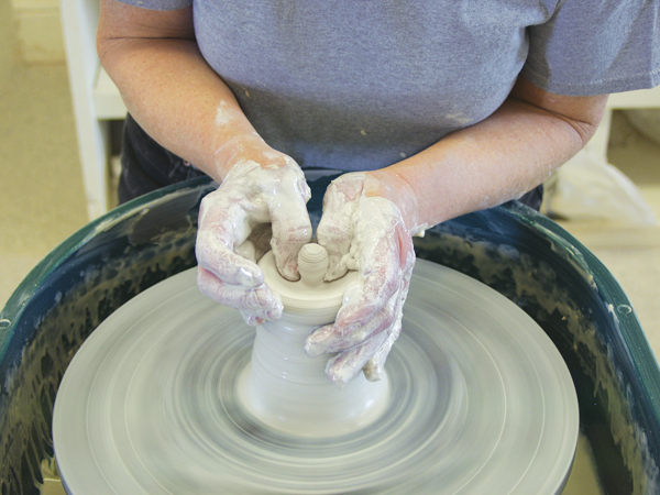 4 To start the lid, center a few ounces of clay at the top of a hump and open it to create a knob.