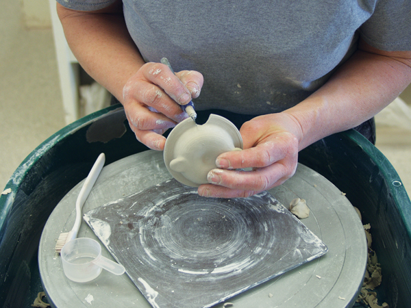 3 Carve out a notch on the rim of the lid between the added balls of clay for a drinking hole.