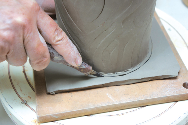 7 Cut around the base of the pot while rotating it on a banding wheel, leaving a 1⁄8-inch border around the pot.