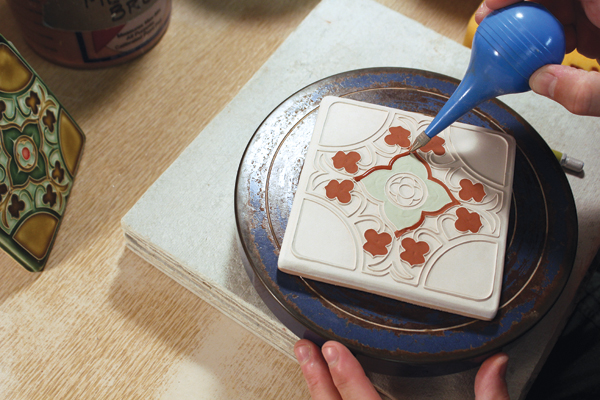 11 Spray water on the bisque-fired tile so the glaze flows evenly, then use a filled bulb syringe to glaze in between the raised lines.