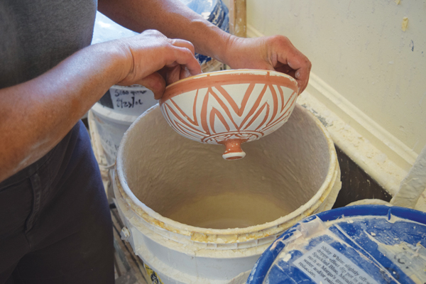 13 Dip the lid upside-down into the second glaze. Dip the plate as well. Blowing on the wet glaze encourages it to pull off the wax.