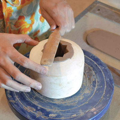 5 Lightly paddle the excess clay flat onto the curved part of the mold.