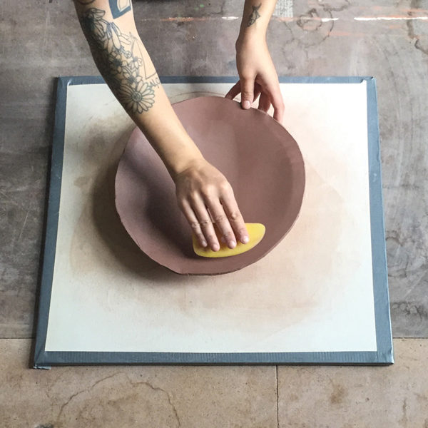 3 Use a rib to compress the slab into the mold. Mark the half-way point on the slab and trace an oval from point to point.