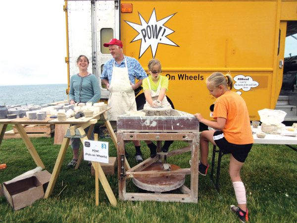 Hannah Niswonger and Sam Taylor watch as a youthful team works together on the treadle wheel during a POW! event in Newport, Massachusetts. Photo: Hayne Bayless.