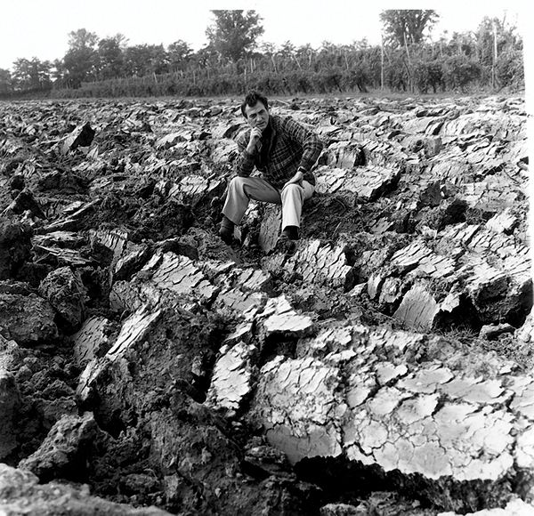 Carlo Zauli sitting in a newly plowed vineyard with fresh clumps of clay—inspiration for his sculptural ceramic work.