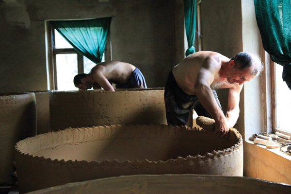 A qvevri maker adding a fat coil to a vessel. Photo: Billy Ray Mangham.