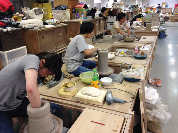 1 Students working on large pots as part of the midterm throwing exam.