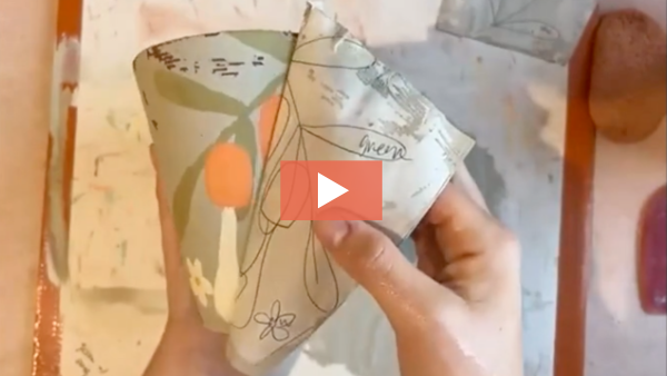 Lakyn Bowman peels back newsprint to reveal a monoprinted design on a mug.