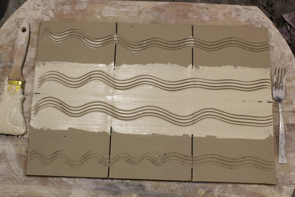 3 Test tiles with added white slip and wavy incised lines made using a fork for texture. Cut the slab into six equally sized tiles.